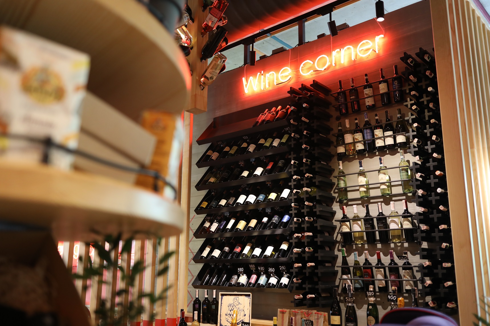 Wine corner with bottles of wine displayed on shelves and a neon sign